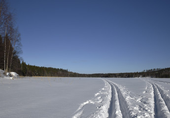 Fototapeta na wymiar Two ski trails on a lake with blue sky in background