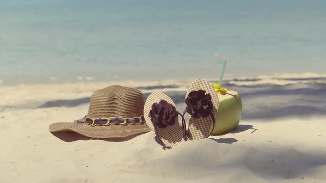 Women's hat, flip-flops and coconut , lonely lying on the sand near the sea.