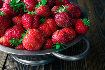 Colander with fresh strawberry on wooden background