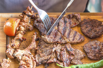 Well-done grilled marinated beef flank steak on wooden board
