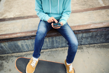 young skateboarder use cellphone  at skatepark