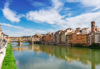 Fototapeta na wymiar Ponte Santa Trinita bridge and Ponte Vecchio bridge with medieval houses over the water of Arno River, Florence, Italy