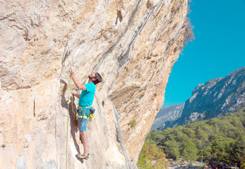 Fototapeta premium Mature male Climber making Move on vertical Rock