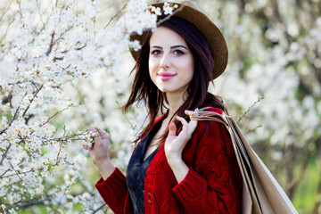 beautiful young woman with shopping bags standing in front of wonderful blooming trees background