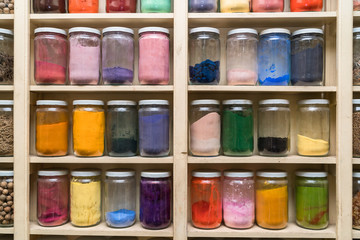 Glass bottles with colorful spices on the shelfs