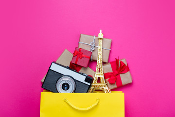cute gifts, camera and beautiful eiffel tower shaped toy in shopping bag and cool laptop on...