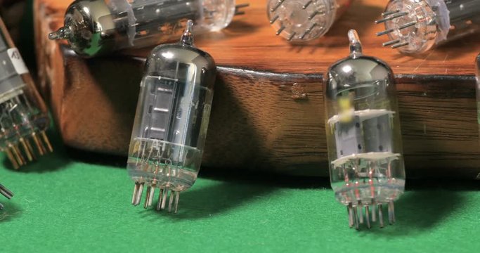 Dolly close up view of a collection of vintage vacuum tubes (valves) tor music amplifiers manufactured in the forties