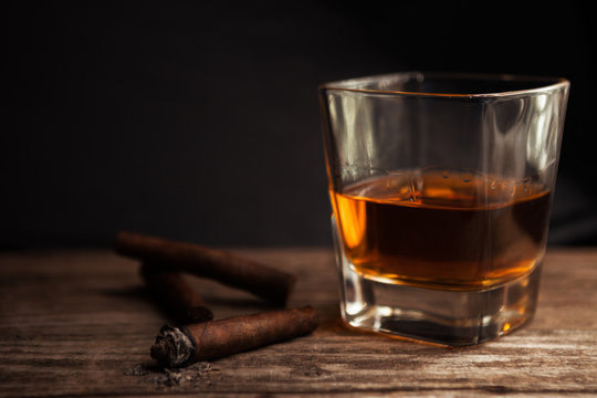 Cigar and glass with brandy on the table