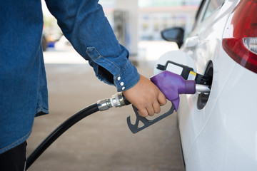 To fill the machine with fuel. Gas station pump. Man filling gasoline fuel in car holding nozzle. Close up.