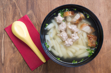 Pork noodle soup on wooden table.
