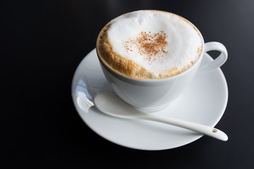 Cappuccino coffee cup with foam on black background