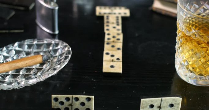 Dolly push in view: Playing a game of domino with a glass of whiskey and a cigar