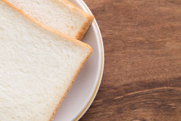 Sliced bread in plate on wooden background.