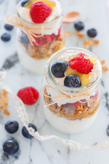 breakfast with yogurt and cereal flakes and raspberries with blueberries. a mixture of yogurt, cereal, berries in a glass jar batch. Rustic food background