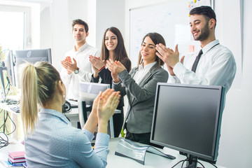 Cheerful business people applauding at business meeting in office.
