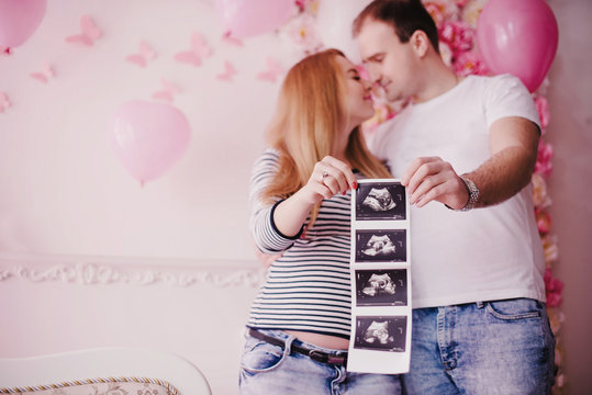 Pregnant woman and husband holding ultrasound photo of baby