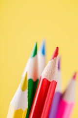 Fototapeta premium Close up of color pencils with different color over yellow background