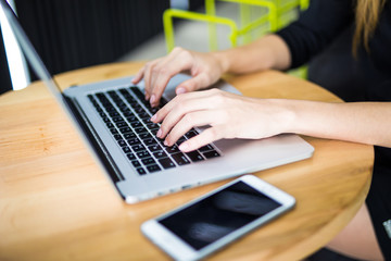 Female hands typing on computer keyboard, phone on table