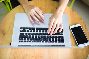 Female hands typing on computer keyboard and phone from top