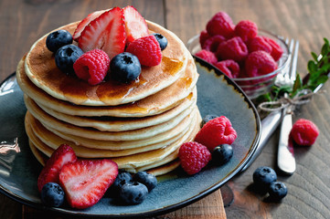  Pancakes with fresh berries and maple syrup for breakfast, selective focus, toned image