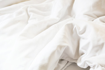 white pillow on bed and with wrinkle messy blanket in bedroom, from sleeping in a long night.