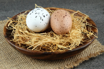 Easter eggs on wooden plate with hay.