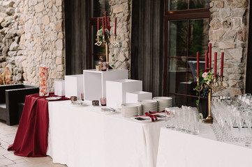 Wedding decoration of the table with red candles, candlesticks, white plates