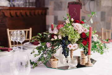 Wedding table decoration with the red, pink flowers and candles