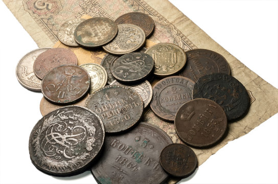 The old copper and silver coins lay on the old bills. On a white background.