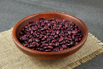 Purple dried beans in a wooden bowl.