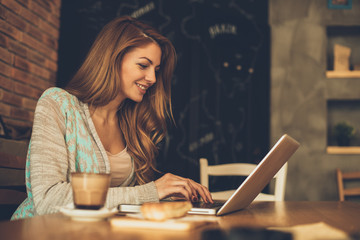 Young woman typing on laptop in cafe