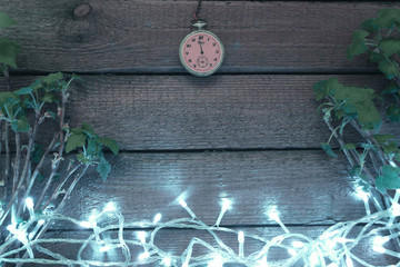 Old clock on the wooden background with the plant branches