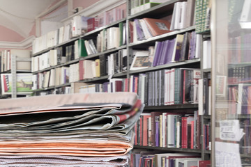 Newspapers stacked on book store, library background. Copy space.