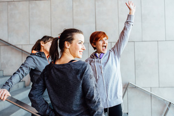 fitness, sport, people and lifestyle concept - smiling three woman waving someone outdoors on city street