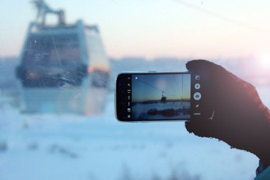 Young woman holding a phone in his hands and makes the photo the funicular