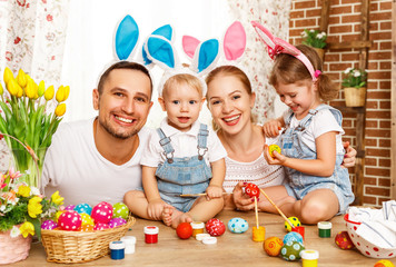 Happy easter! family mother, father and children paint  eggs for holiday.