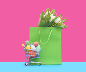 Easter eggs in shopping cart and green bag with tulips