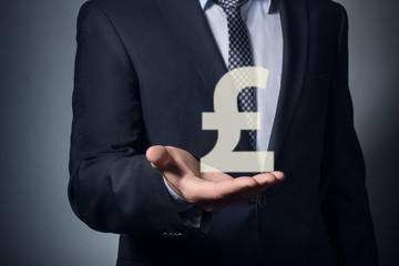 businessman holding currency symbol in hands. hand holding a pound symbol.