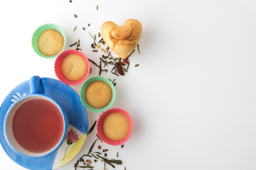 Cup of tea with a heart cake and silicon baking dishes. White background.