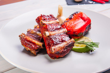 Close up Barbecue pork ribs and vegetables on the white plate on the wooden background with details. Selective focus