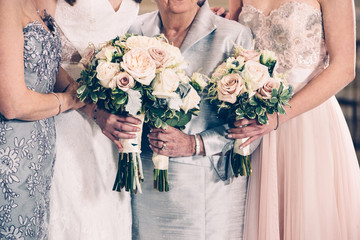 Women generation family and bride holding flowers bunches on wedding day.