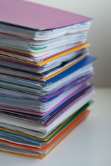 Several multicolored folders with documents stacked in a pile on