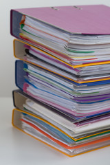 Several multicolored folders with documents stacked in a pile on