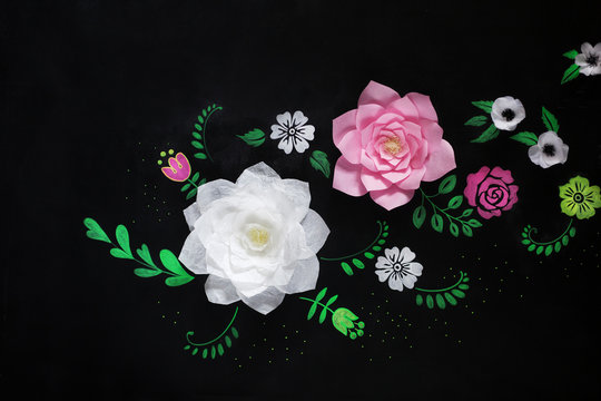 Decorative flowers from paper on a black background.  Drawing chalk on a black board.
