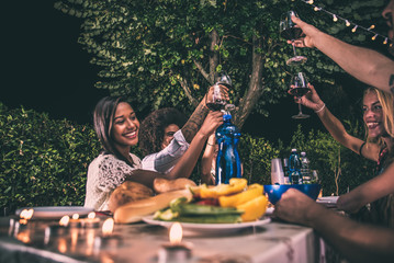Group of friends making barbecue in the backyard at dinner time