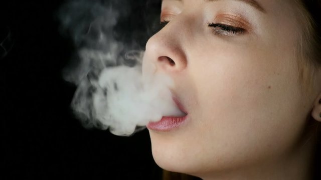 Young Beautiful Woman Smoking Electronic Cigarette On Black Background