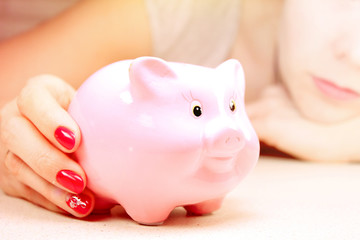 Piggy bank for money in the hand of a young woman