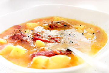 Pea soup in a white plate with potatoes and meat