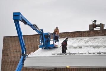 Workers shovelling manually the roof of the building
