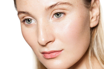 Close-up of a woman's face with a clean well-groomed and shiny skin isolated on white background